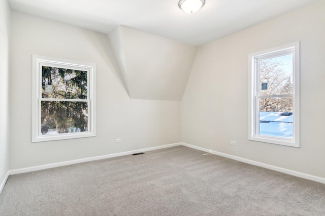 bonus room with vaulted ceiling and light colored carpet