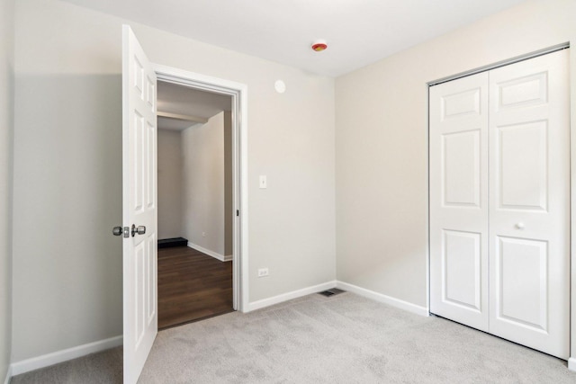 unfurnished bedroom with light colored carpet and a closet