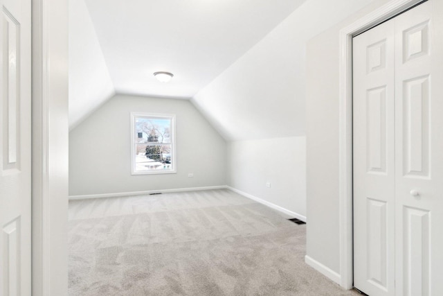 bonus room with lofted ceiling and light colored carpet