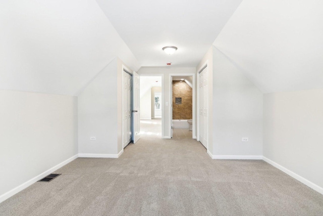 bonus room with lofted ceiling and light carpet