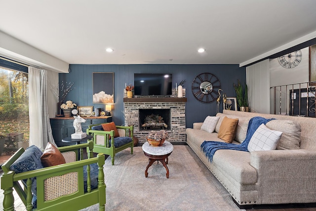 living room with a stone fireplace and wooden walls