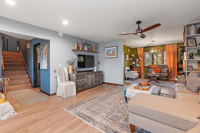 living room featuring ceiling fan with notable chandelier and light hardwood / wood-style floors