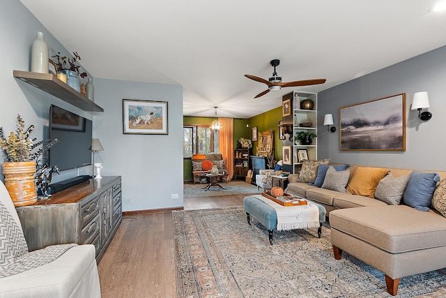 living room with ceiling fan with notable chandelier and light hardwood / wood-style flooring