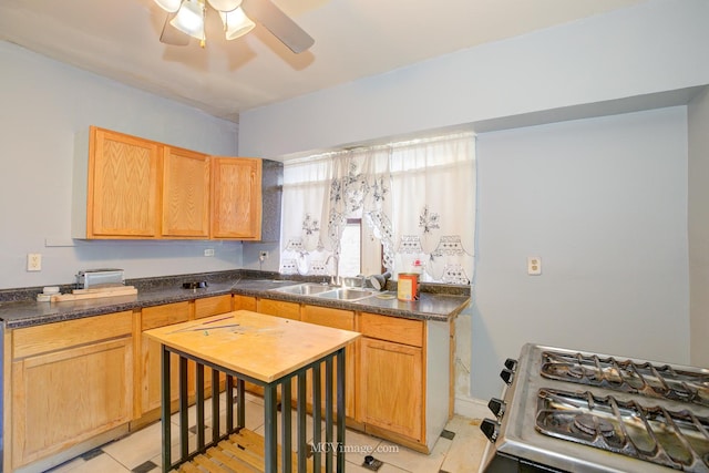 kitchen with ceiling fan, sink, light brown cabinetry, light tile patterned floors, and range