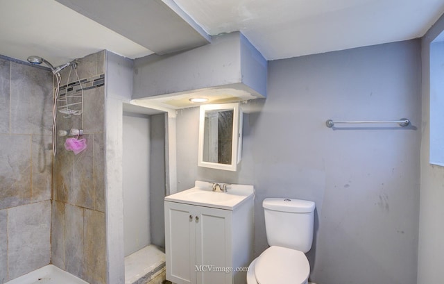 bathroom with toilet, vanity, and tiled shower