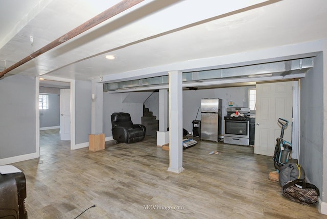 basement featuring hardwood / wood-style floors and stainless steel fridge