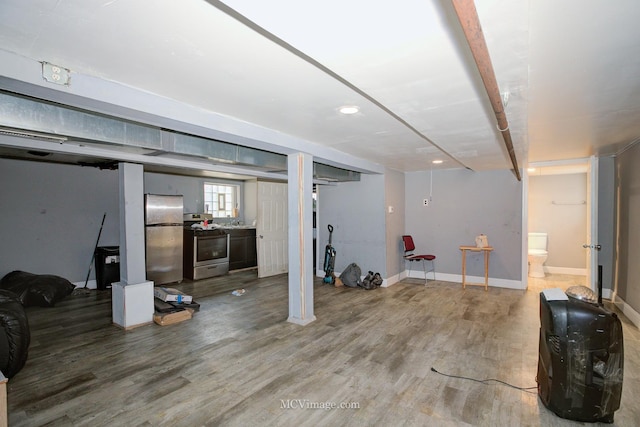 basement with stainless steel refrigerator and hardwood / wood-style floors