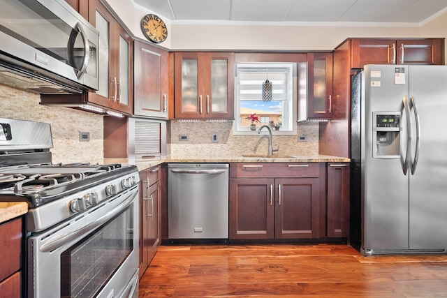 kitchen featuring backsplash, dark wood-type flooring, sink, light stone counters, and stainless steel appliances