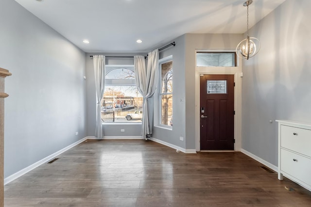 entrance foyer featuring dark hardwood / wood-style flooring, plenty of natural light, and an inviting chandelier