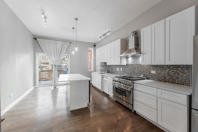 kitchen with pendant lighting, a center island, white cabinets, wall chimney range hood, and appliances with stainless steel finishes