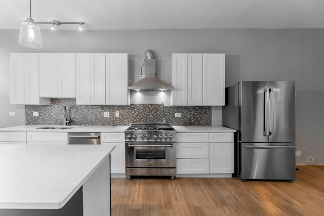 kitchen featuring white cabinets, appliances with stainless steel finishes, sink, and wall chimney range hood