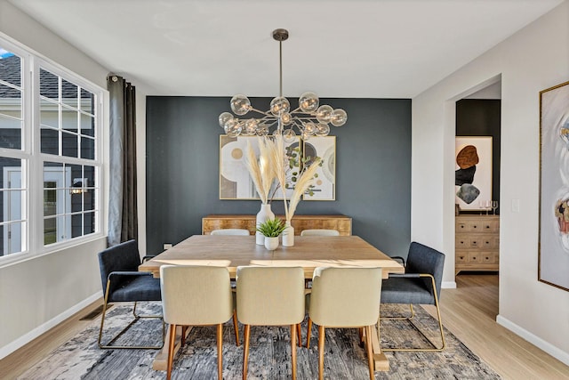 dining space featuring light hardwood / wood-style floors and a notable chandelier