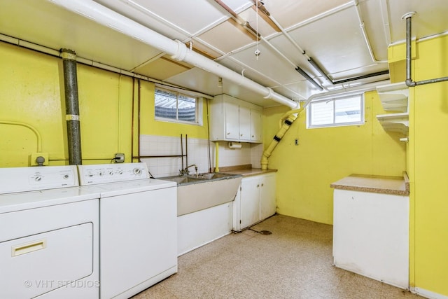 washroom with cabinets, washing machine and dryer, and sink