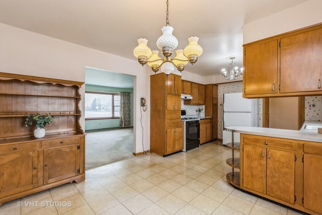 kitchen with white refrigerator, hanging light fixtures, range with gas cooktop, light colored carpet, and a chandelier