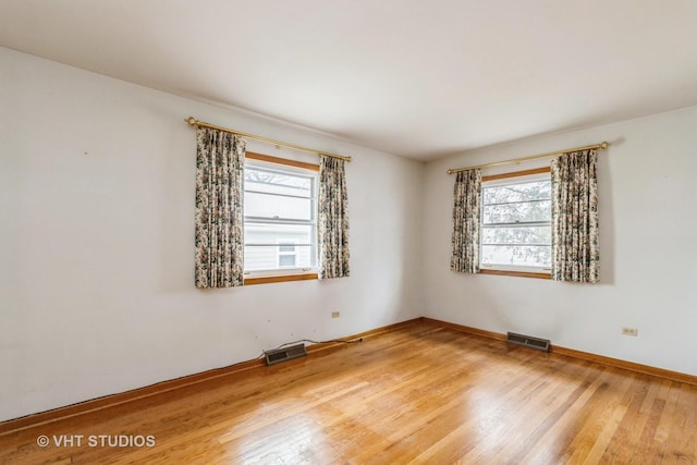 empty room with a healthy amount of sunlight and wood-type flooring