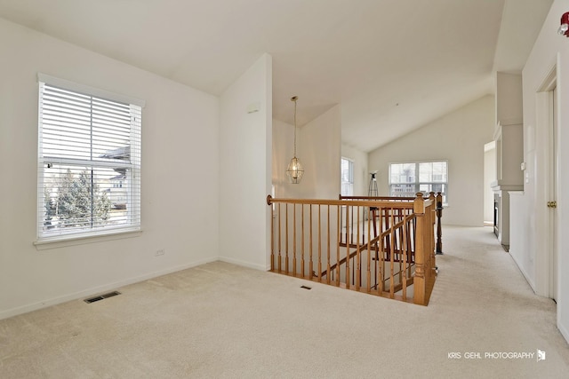 empty room featuring light colored carpet and vaulted ceiling