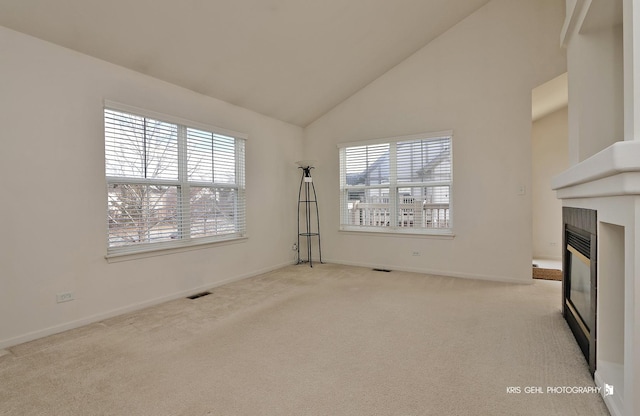 unfurnished living room featuring light carpet and high vaulted ceiling