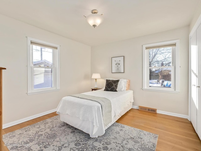 bedroom with multiple windows and hardwood / wood-style flooring