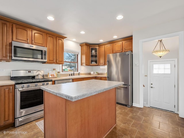 kitchen with sink, stainless steel appliances, decorative light fixtures, and a kitchen island