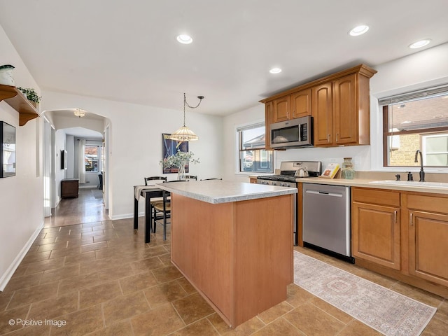 kitchen with stainless steel appliances, a center island, pendant lighting, a wealth of natural light, and sink