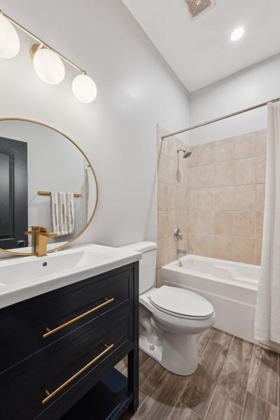 full bathroom featuring shower / bath combination with curtain, toilet, and vanity