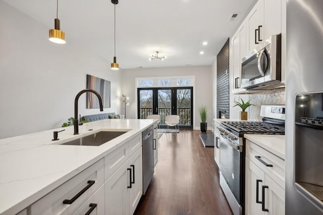 kitchen featuring sink, white cabinets, decorative light fixtures, and appliances with stainless steel finishes