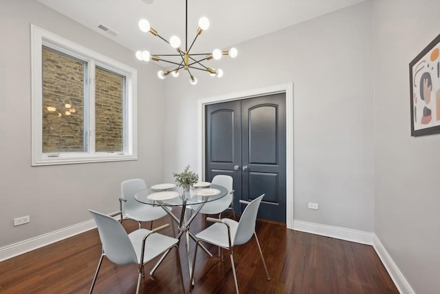 dining space featuring dark wood-type flooring and an inviting chandelier