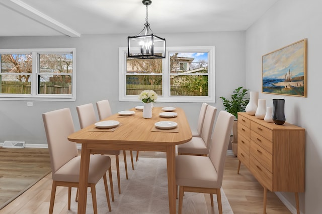 dining space featuring light wood-type flooring and an inviting chandelier