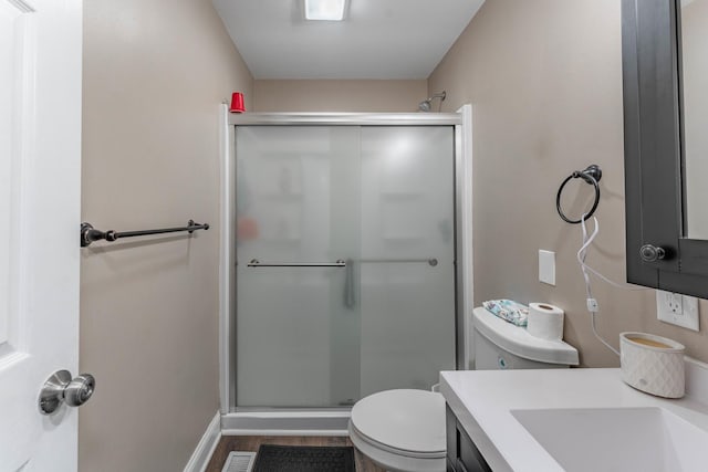 bathroom featuring vanity, hardwood / wood-style flooring, toilet, and an enclosed shower