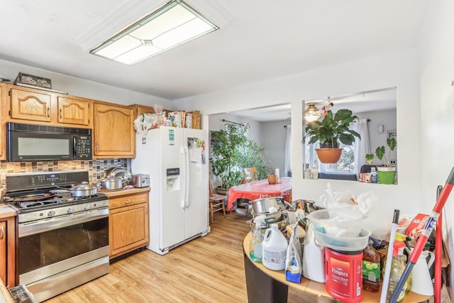 kitchen featuring white refrigerator with ice dispenser, light wood-type flooring, gas stove, and decorative backsplash