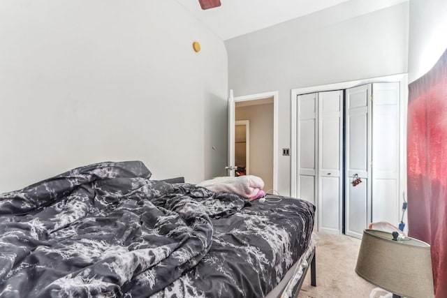 bedroom with ceiling fan, vaulted ceiling, light carpet, and a closet