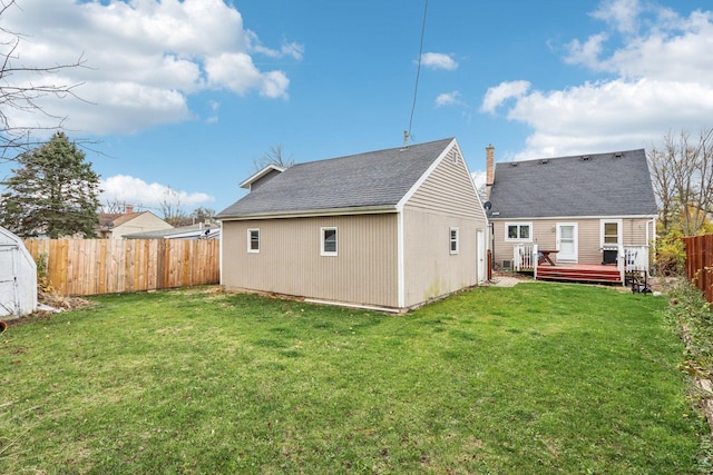 rear view of house featuring a storage shed, a deck, and a yard