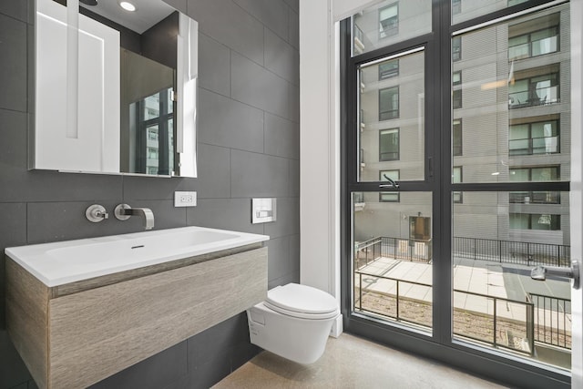 bathroom featuring vanity, toilet, and tile walls