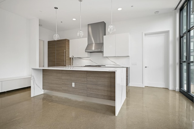 kitchen featuring decorative backsplash, white cabinetry, hanging light fixtures, and wall chimney range hood