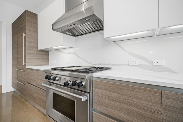 kitchen with wall chimney exhaust hood, light stone countertops, and high end stainless steel range