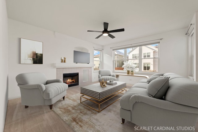 living room with ceiling fan and a tile fireplace