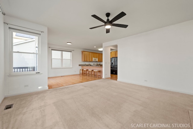 unfurnished living room featuring ceiling fan and light colored carpet