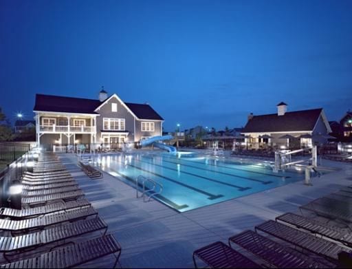 pool at night featuring a water slide and a patio