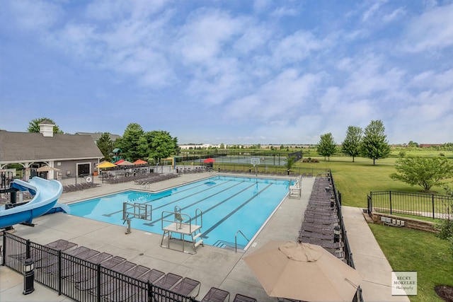 view of pool with a lawn, a water slide, and a patio