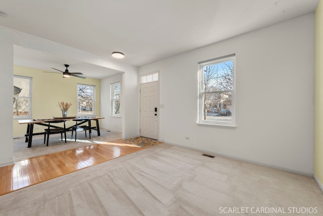 foyer entrance with light colored carpet and ceiling fan