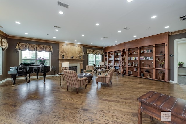 living room with a fireplace, hardwood / wood-style flooring, built in features, and ornamental molding