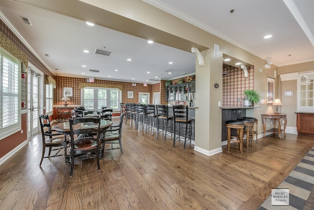 dining area with wood-type flooring, ornamental molding, and brick wall