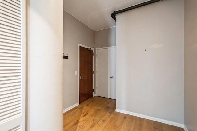 corridor with light wood-style floors and baseboards