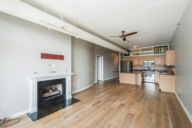 kitchen featuring light wood-type flooring, appliances with stainless steel finishes, dark countertops, and decorative backsplash