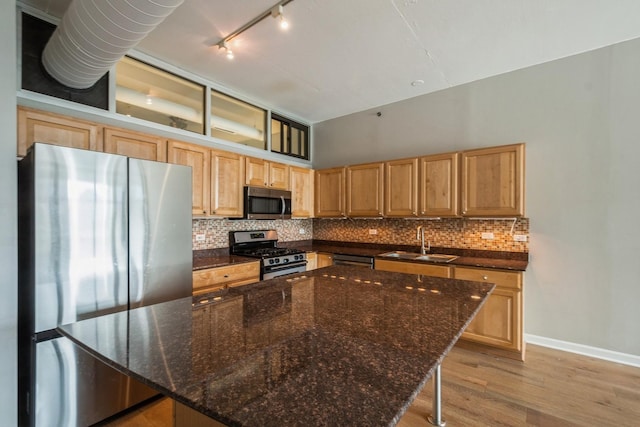 kitchen featuring tasteful backsplash, appliances with stainless steel finishes, a sink, and a center island