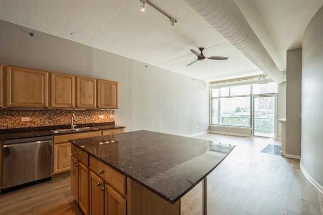 kitchen featuring light wood finished floors, backsplash, a kitchen island, a sink, and dishwasher