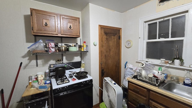 kitchen featuring heating unit, sink, and white range with gas stovetop