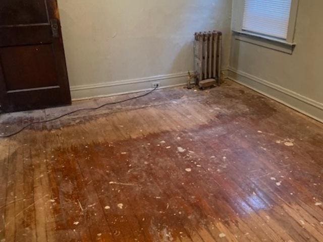 empty room featuring hardwood / wood-style floors and radiator heating unit