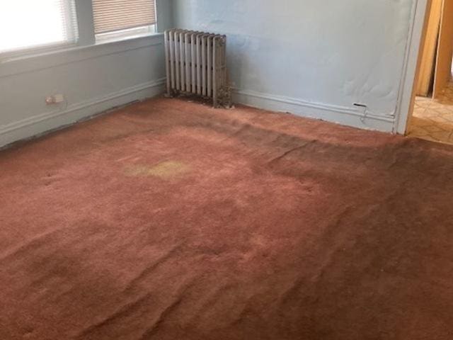 carpeted spare room with radiator heating unit