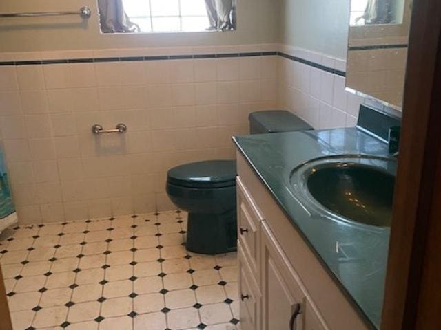 bathroom with vanity, toilet, and tile walls